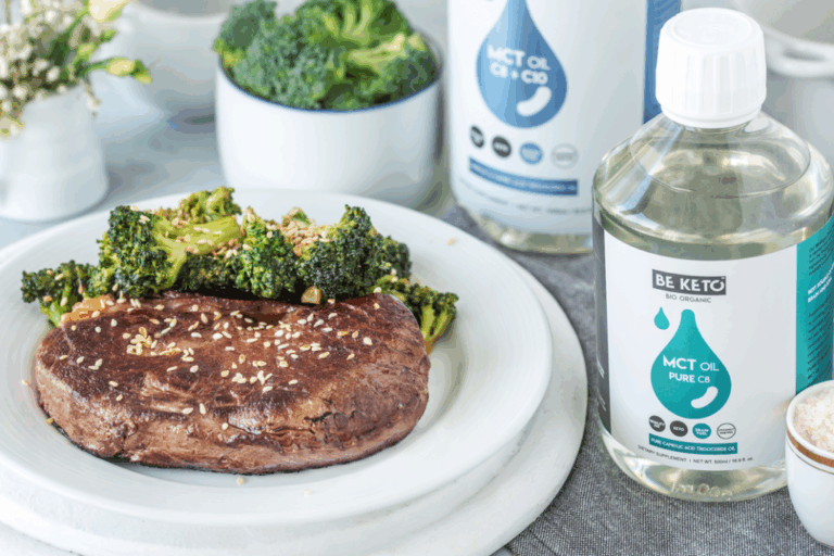 Biały talerz, na talerzu przygotowany azjatycki stek z brokułami, posypany sezamem. W tle miseczka z brokułami i olej MCT C8+C10, obok olej MCT C8